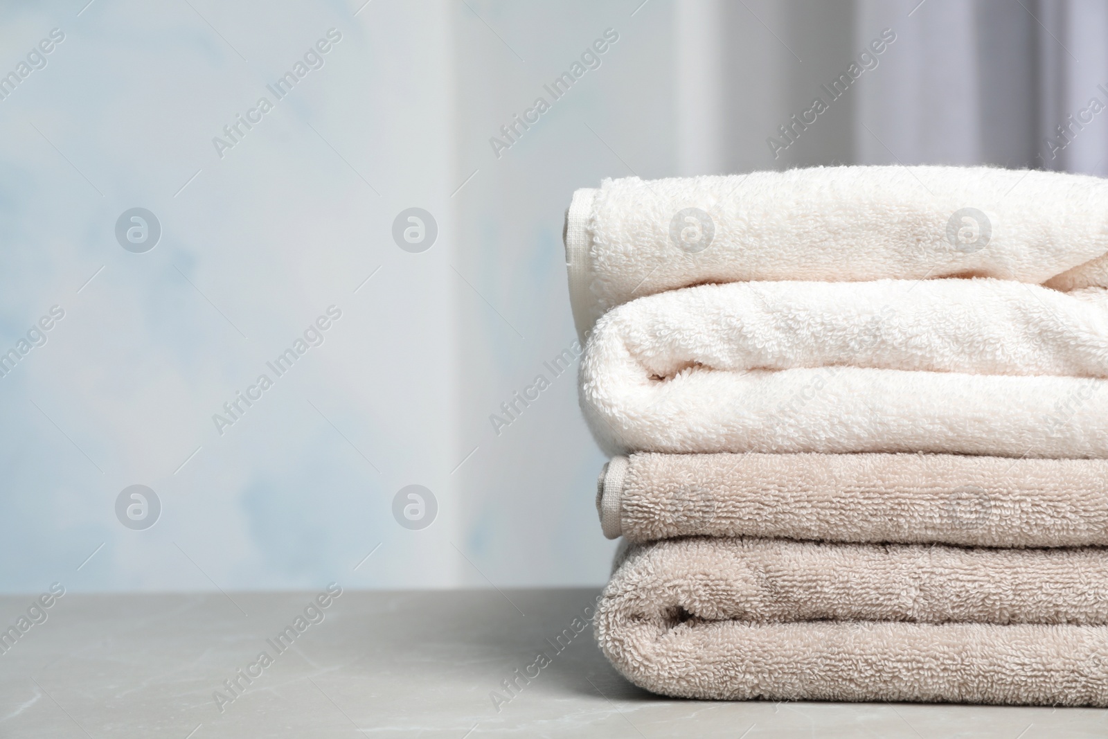 Photo of Stack of soft bath towels on table against blurred background. Space for text