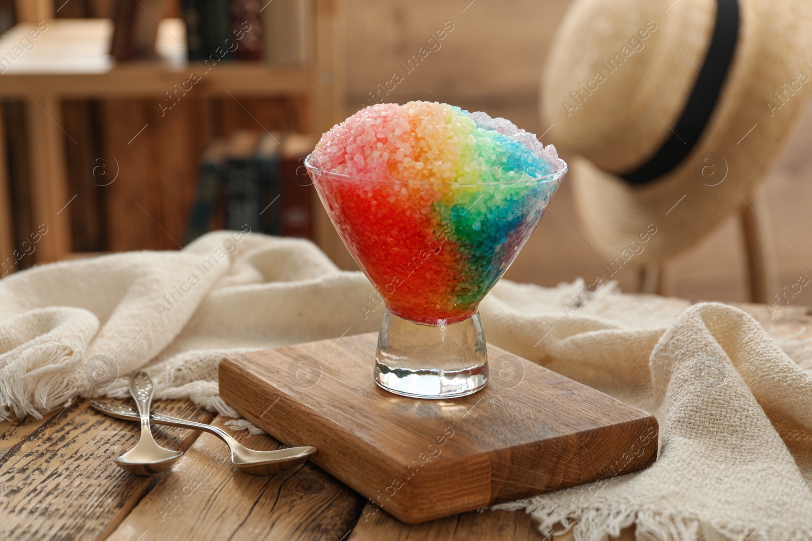 Photo of Rainbow shaving ice in glass dessert bowl on wooden  table indoors