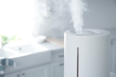 Photo of Modern air humidifier in kitchen, closeup. Space for text