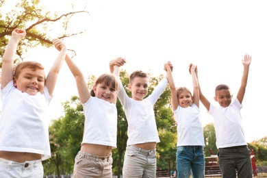 Photo of Group of children holding hands up in park. Volunteer project