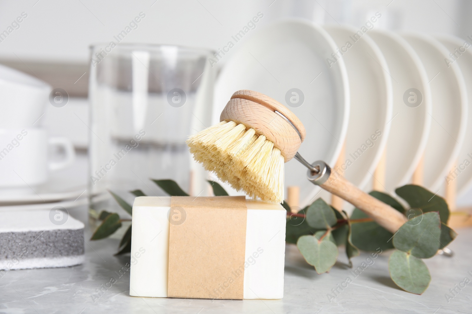 Photo of Cleaning brush and soap bar for dish washing on grey marble table, closeup