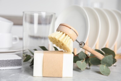 Photo of Cleaning brush and soap bar for dish washing on grey marble table, closeup