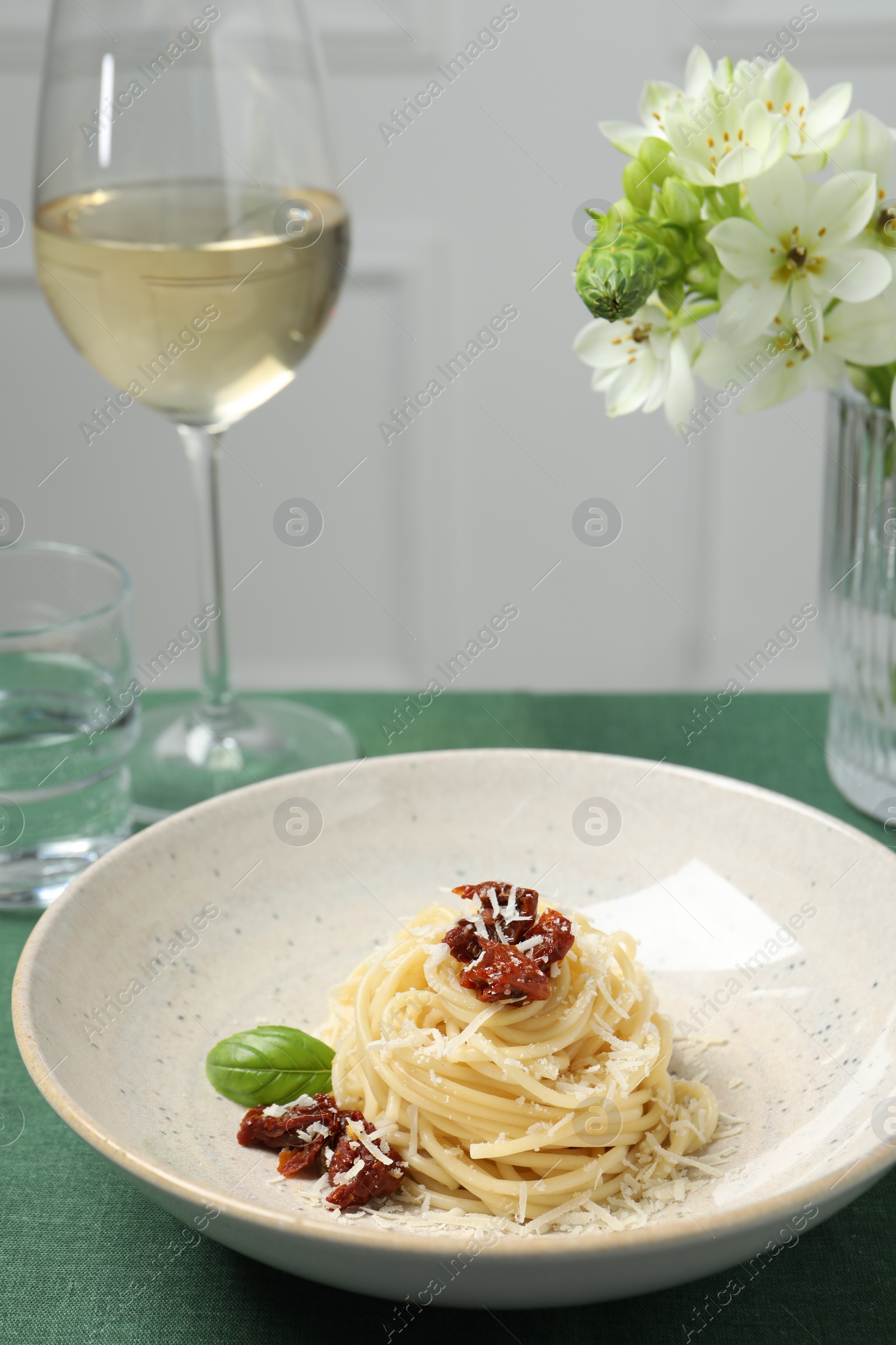 Photo of Tasty spaghetti with sun-dried tomatoes and parmesan cheese served on table, closeup. Exquisite presentation of pasta dish