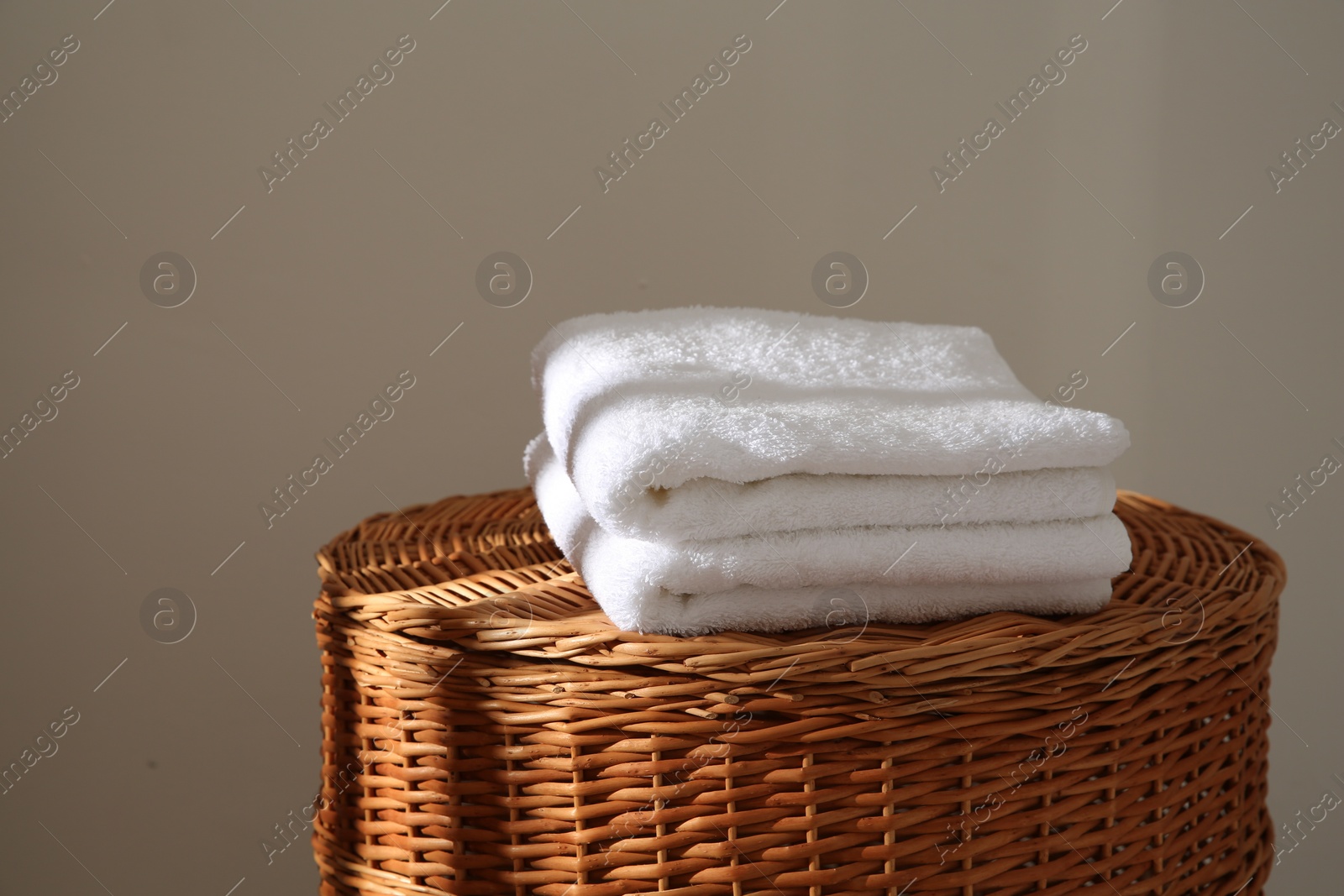 Photo of Soft towels on wicker basket indoors, space for text