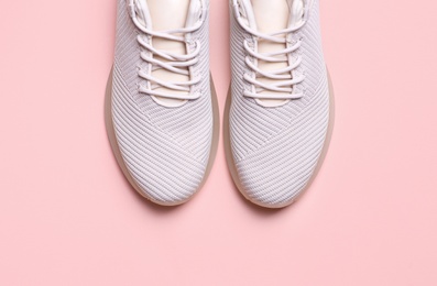 Stylish sporty sneakers on pink background, top view