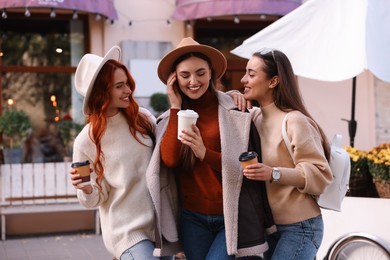 Photo of Happy friends with paper cups of coffee spending time together on city street