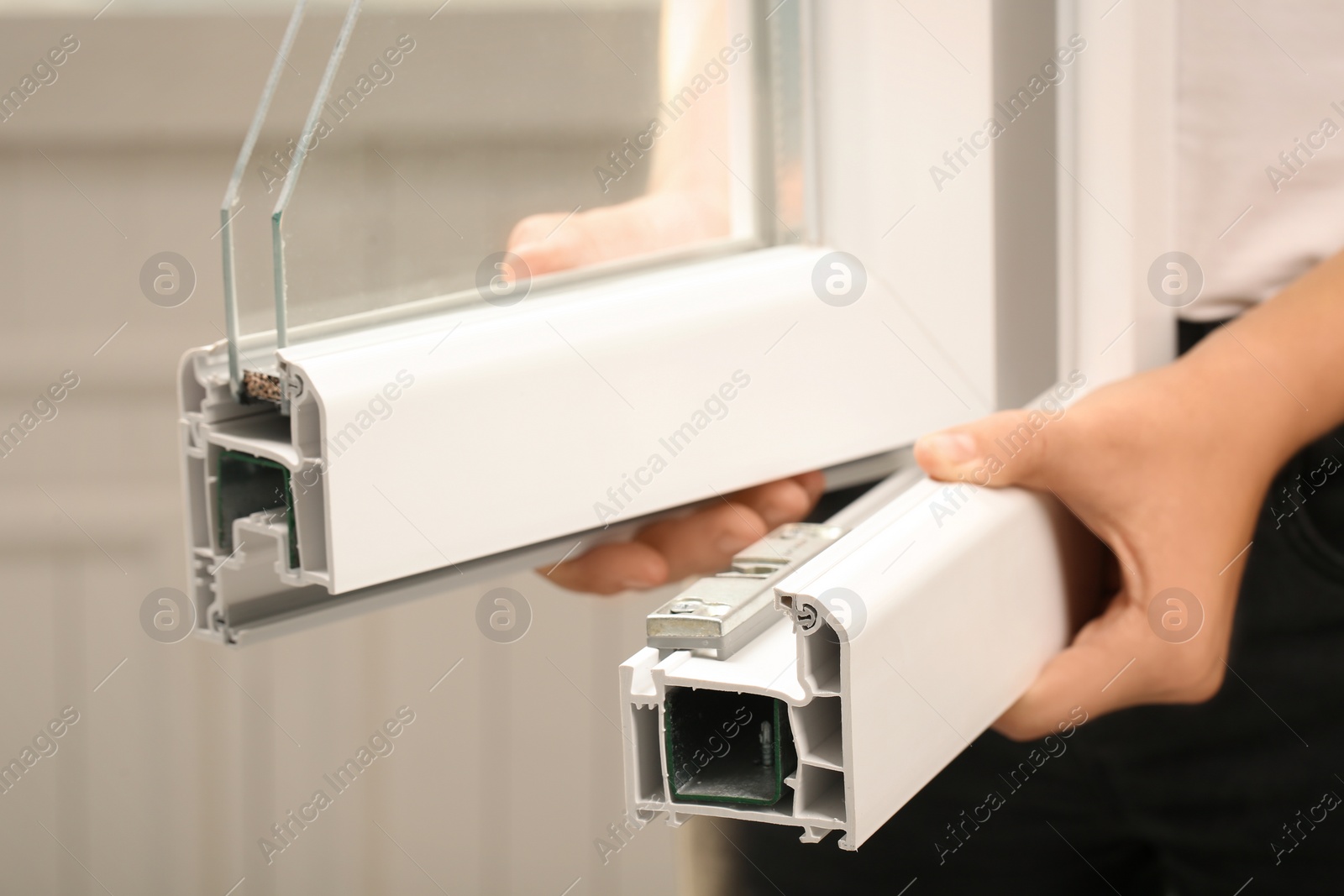 Photo of Woman holding sample of modern window profile on blurred background, closeup