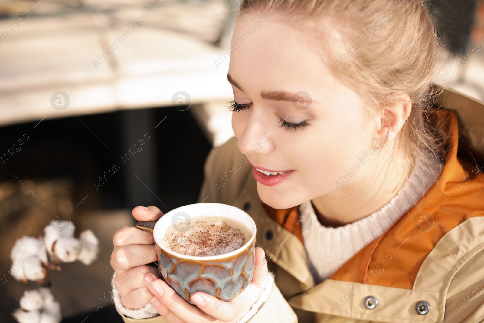 Photo of Young woman enjoying tasty coffee outdoors, closeup