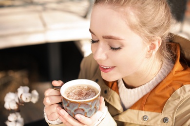 Young woman enjoying tasty coffee outdoors, closeup