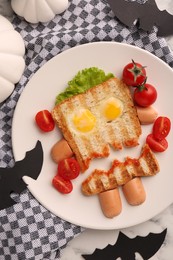 Cute monster sandwich with cherry tomatoes, fried eggs and sausages on white marble table, flat lay. Halloween snack