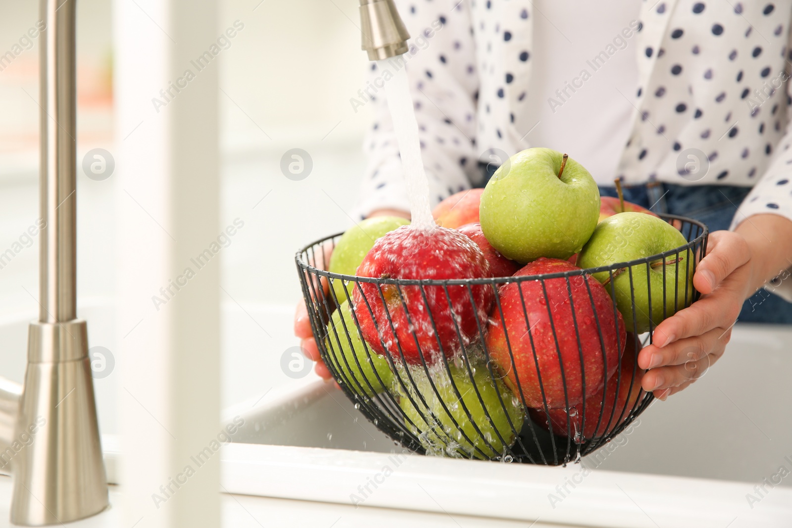 Photo of Woman washing fresh apples in kitchen sink, closeup