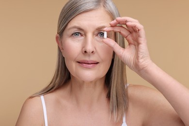 Photo of Beautiful woman with vitamin capsule on beige background