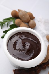 Photo of Bowl of tasty tamarind sauce and fresh pods on white table