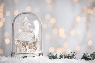 Photo of Beautiful snow globe against blurred Christmas lights. Space for text