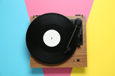 Turntable with vinyl record on color background, top view