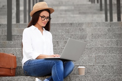 Photo of Beautiful woman with laptop sitting on stairs outdoors