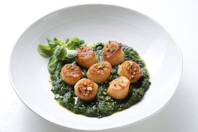 Photo of Delicious fried scallops with tasty sauce and corn salad in bowl on white table, closeup