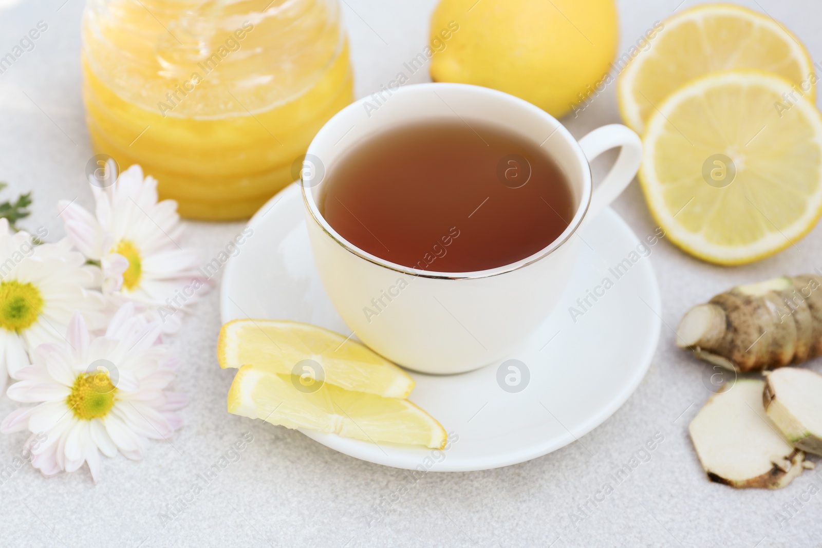 Photo of Cup of delicious tea with honey, lemon and ginger on white table