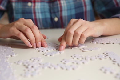 Young woman playing with puzzles at table, closeup