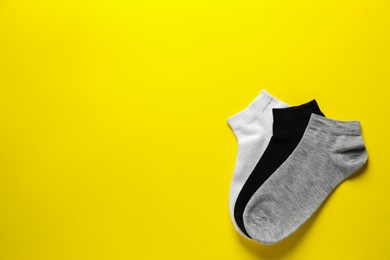 Different socks on yellow background, flat lay. Space for text
