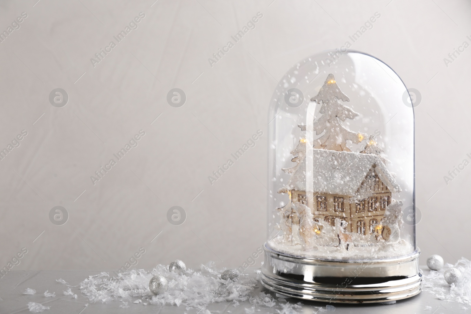 Photo of Beautiful snow globe on grey table against light background, space for text