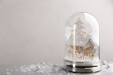 Photo of Beautiful snow globe on grey table against light background, space for text