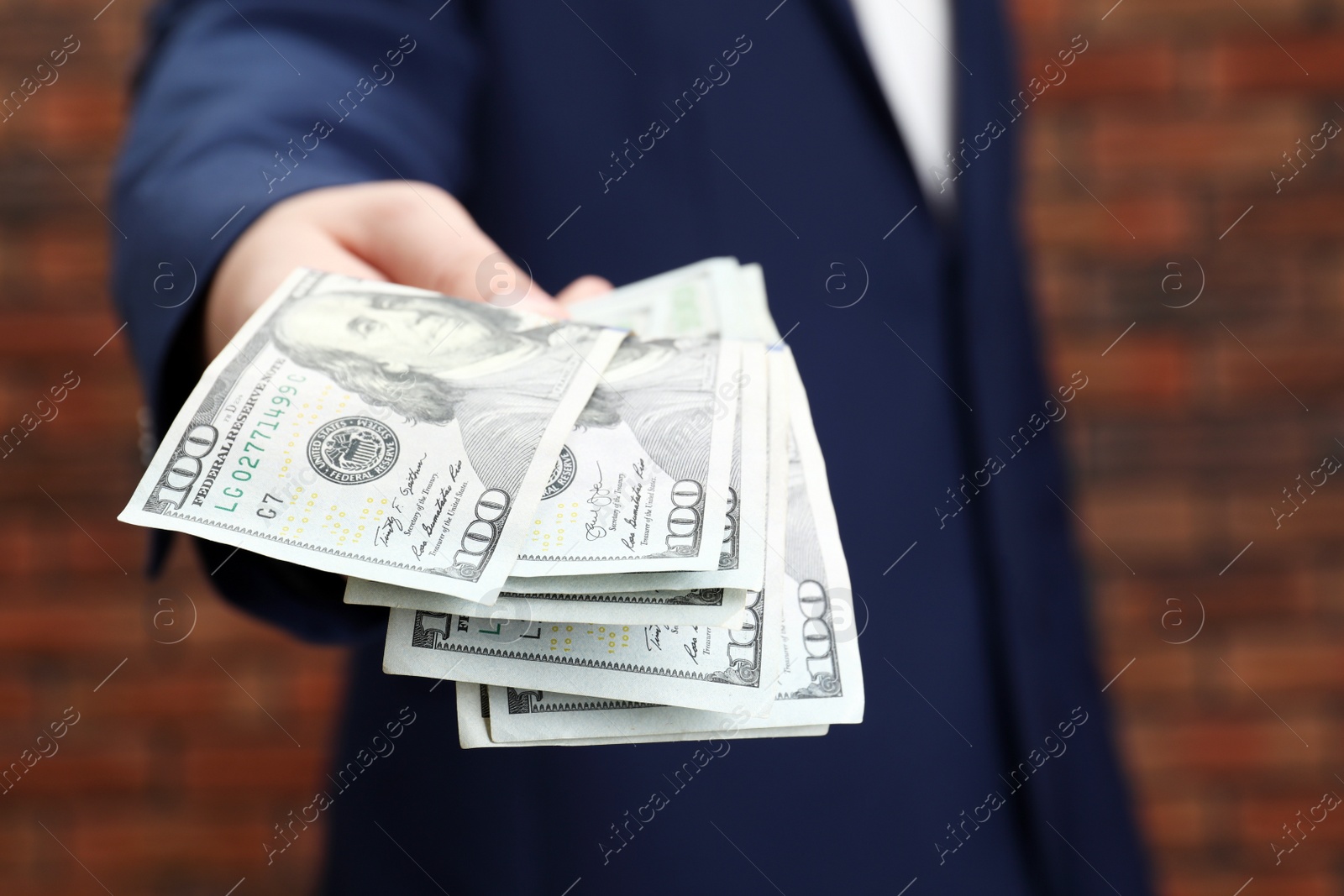 Photo of Man holding money near red brick wall, closeup. Currency exchange