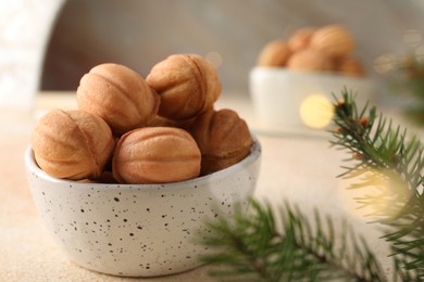 Photo of Delicious nut shaped cookies and fir tree branch on table, closeup