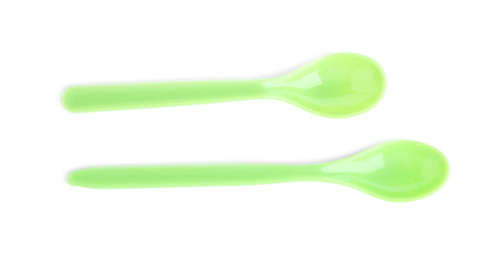 Green plastic spoons isolated on white, top view. Serving baby food