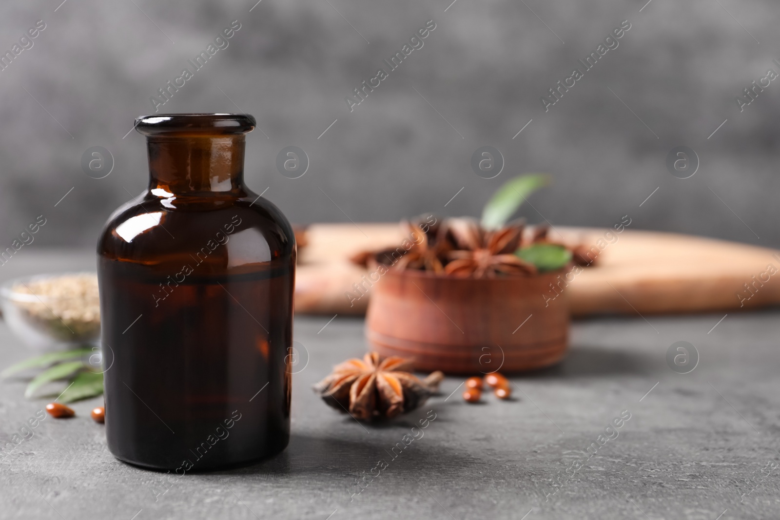 Photo of Bottle of essential oil and anise on grey table. Space for text