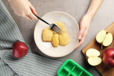 Photo of Woman making apple puree for freezing in cube tray, closeup