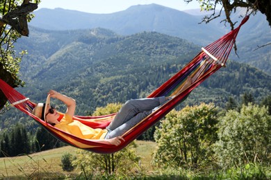 Photo of Young woman resting in hammock outdoors on sunny day