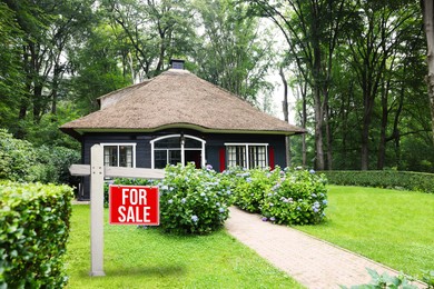 Image of Sale sign near beautiful house outdoors. Red signboard with words