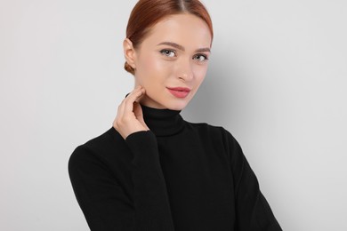 Portrait of beautiful young woman on light gray background