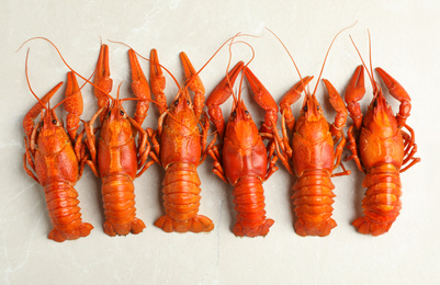 Photo of Delicious boiled crayfishes on light grey marble table, flat lay