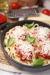 Photo of Delicious pasta with tomato sauce, basil and parmesan cheese on wicker mat, closeup