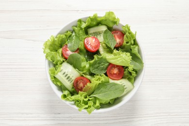 Photo of Delicious vegetable salad on white wooden table, top view