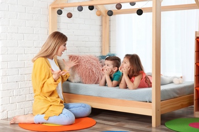 Nanny and little children playing at home