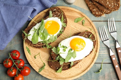 Photo of Delicious sandwiches with arugula and fried egg on blue wooden table, flat lay