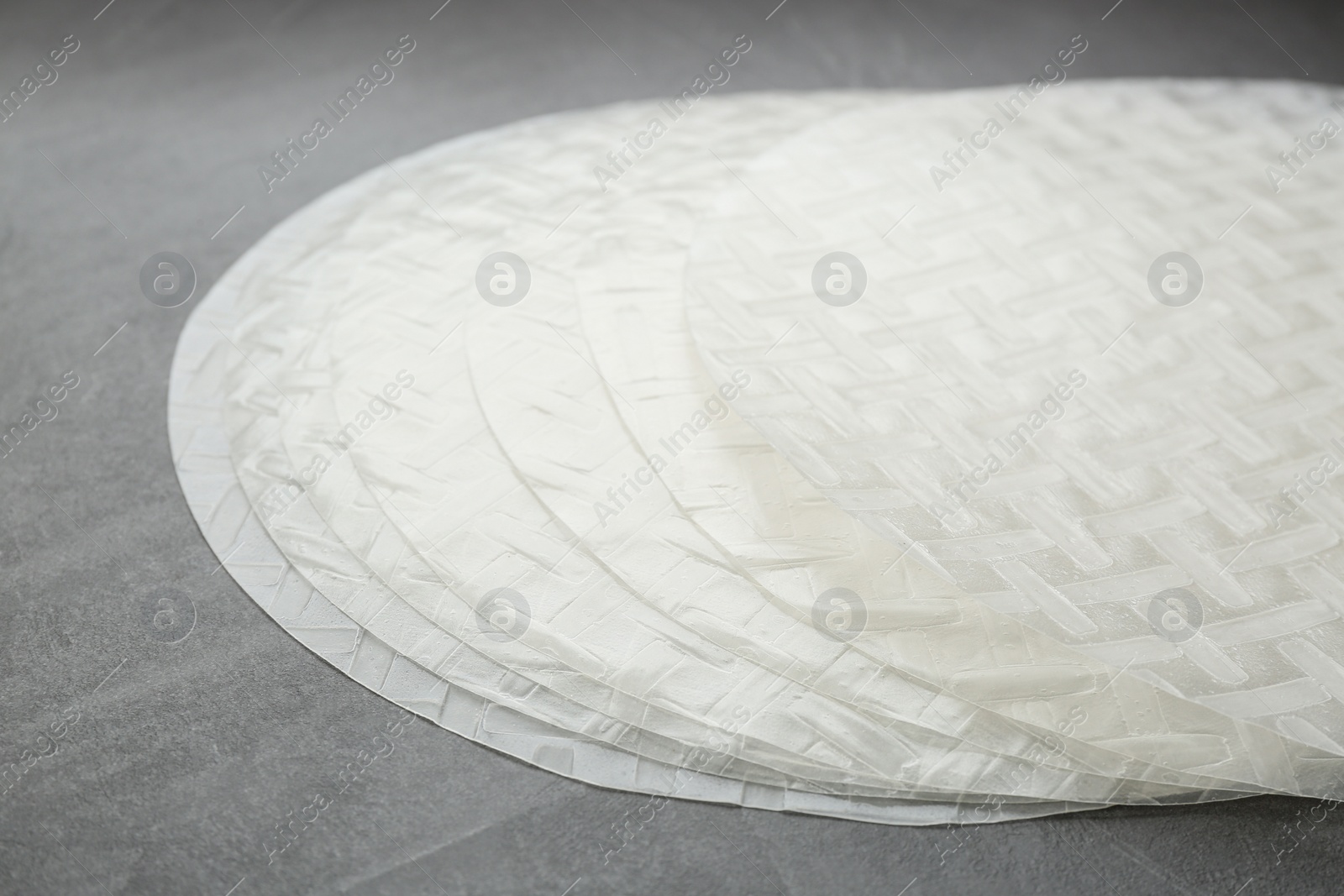 Photo of Sheets of dry rice paper on grey table, closeup