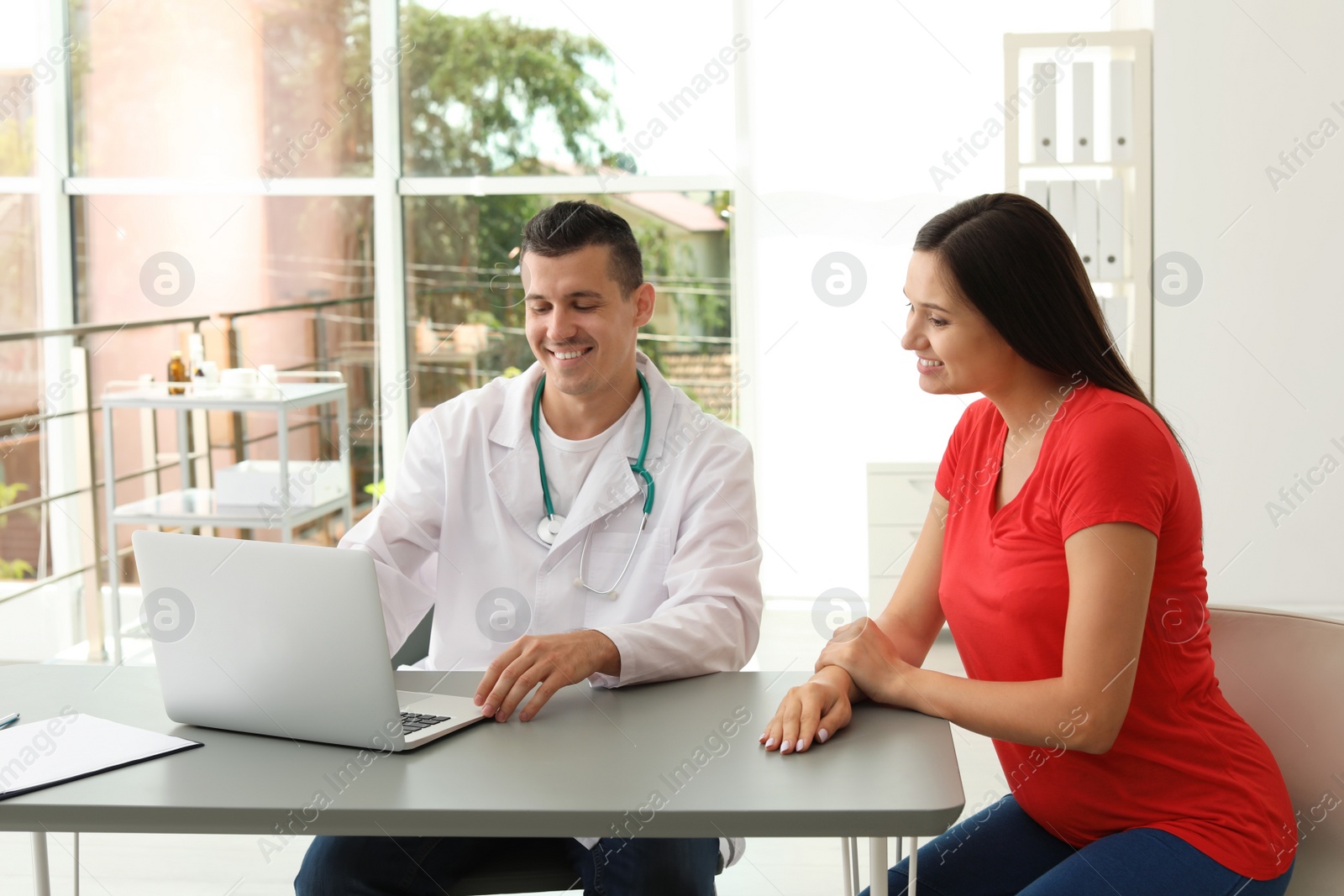 Photo of Young doctor with pregnant woman in hospital. Patient consultation