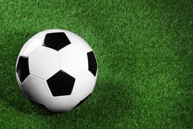 One soccer ball on green grass, space for text. Sports equipment