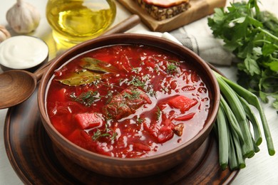 Photo of Stylish brown clay bowl with Ukrainian borsch served on white wooden table