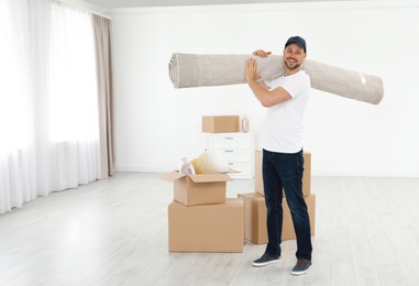 Moving service employees with cardboard boxes and carpet in room