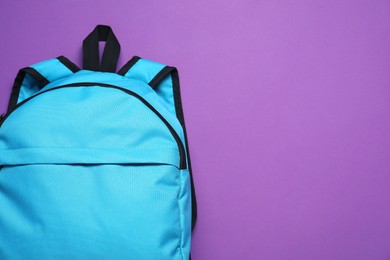 Stylish light blue backpack on purple background, top view. Space for text