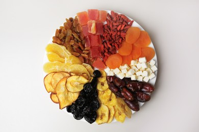 Photo of Plate with different dried fruits on white background, top view