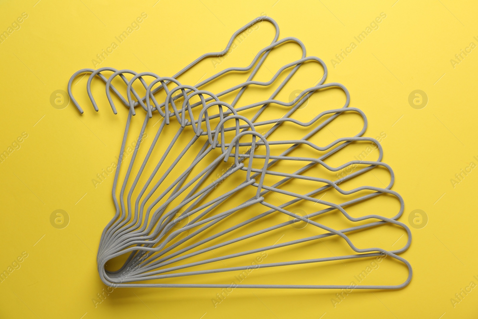 Photo of Empty hangers on yellow background, top view