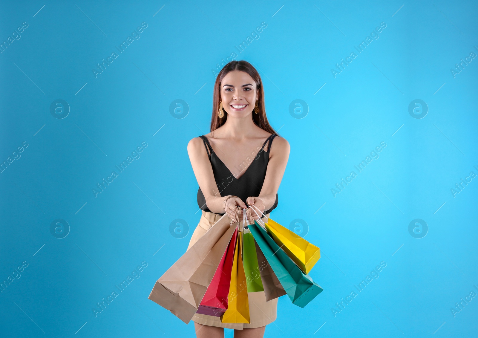 Photo of Young woman with shopping bags on color background