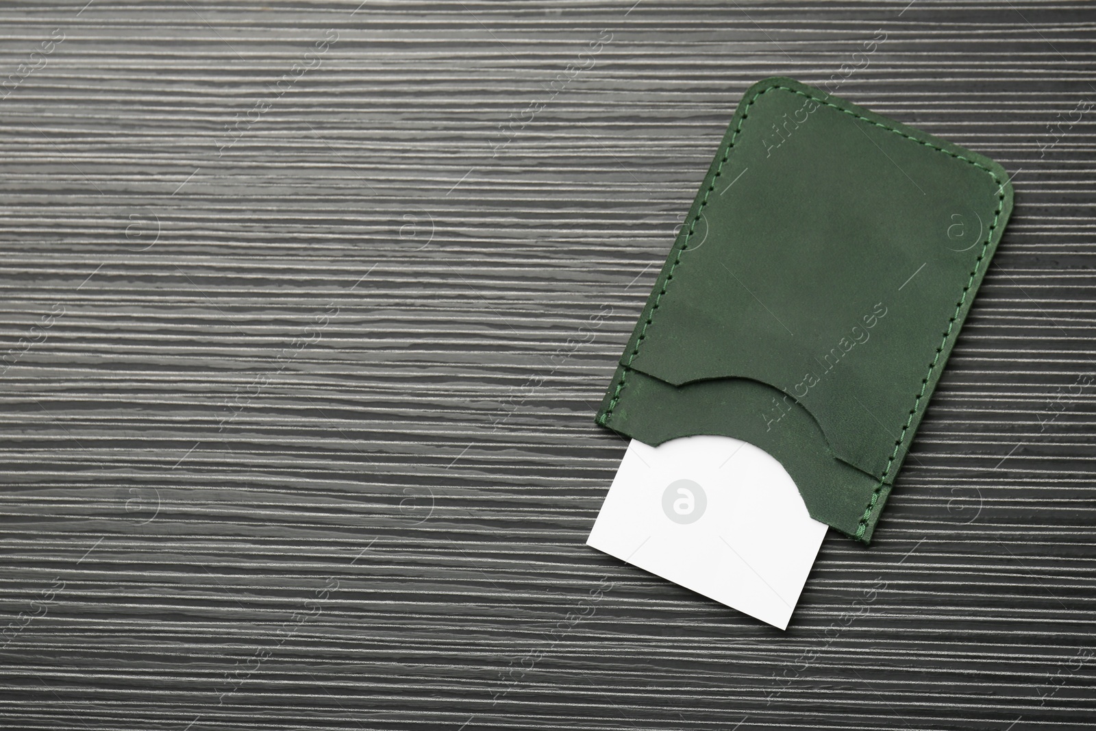 Photo of Leather business card holder with card on grey table, top view. Space for text