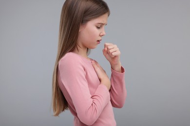 Sick girl coughing on gray background. Cold symptoms